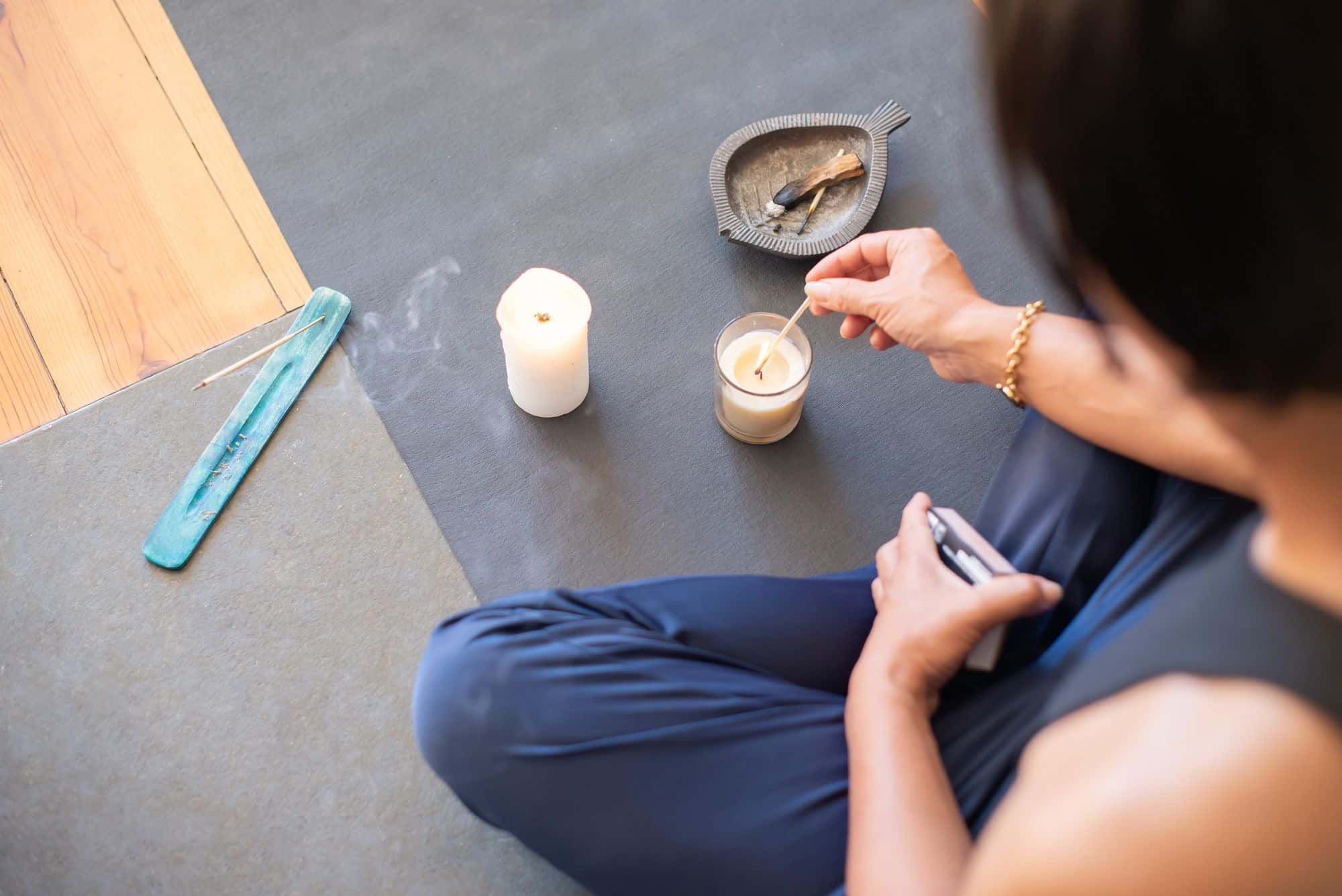 A person lighting a candle in a calm, quiet room