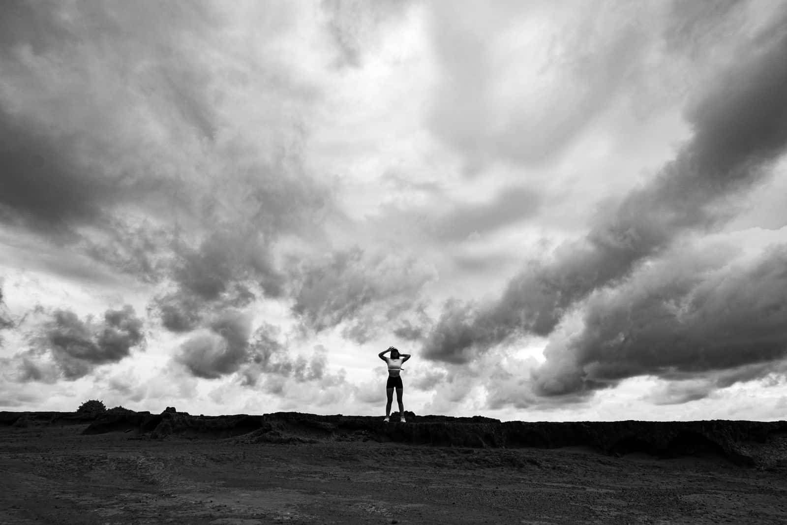 A small figure standing on a hill under a huge cloudy sky