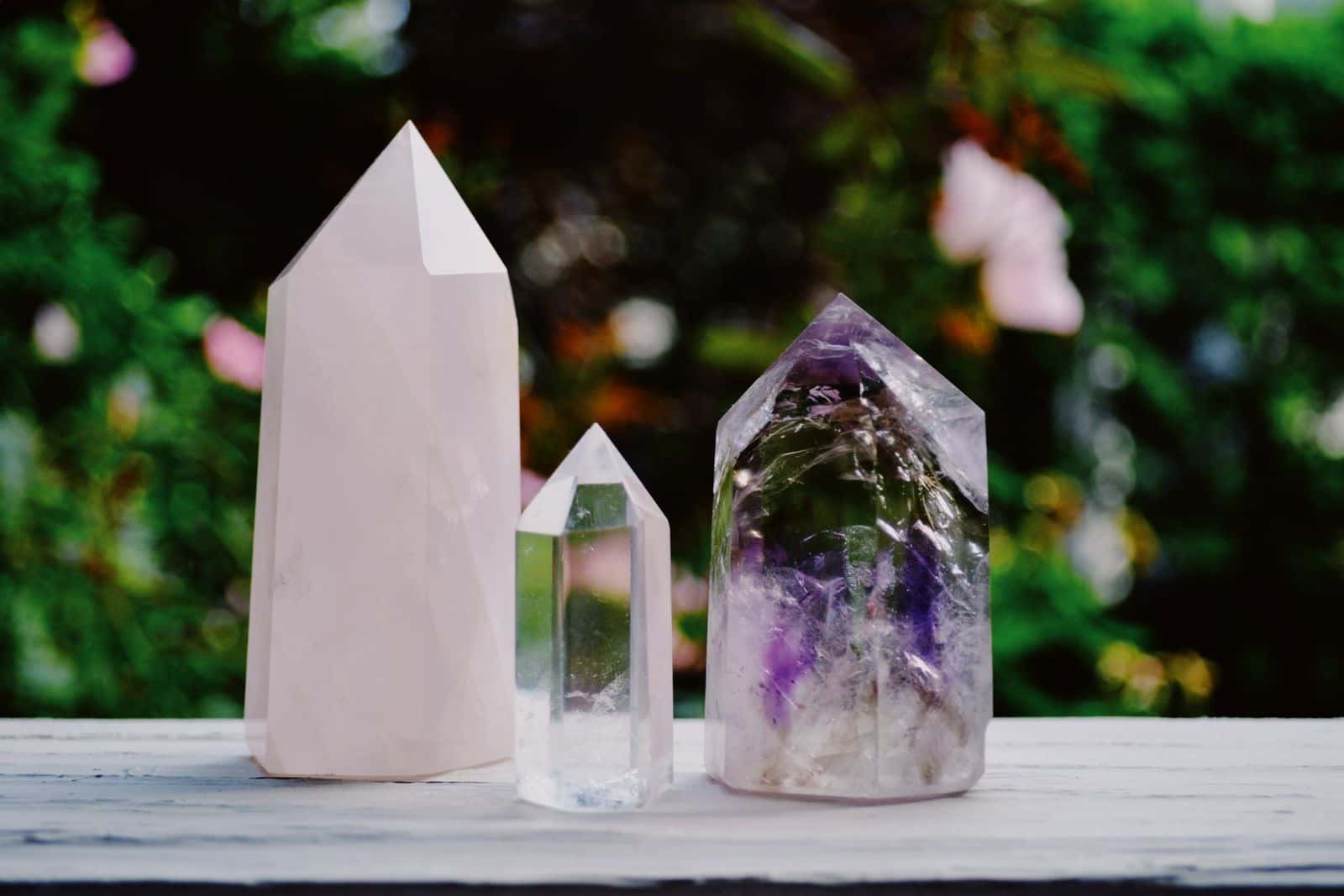 Clear quartz and amethyst crystals standing on a table in a garden