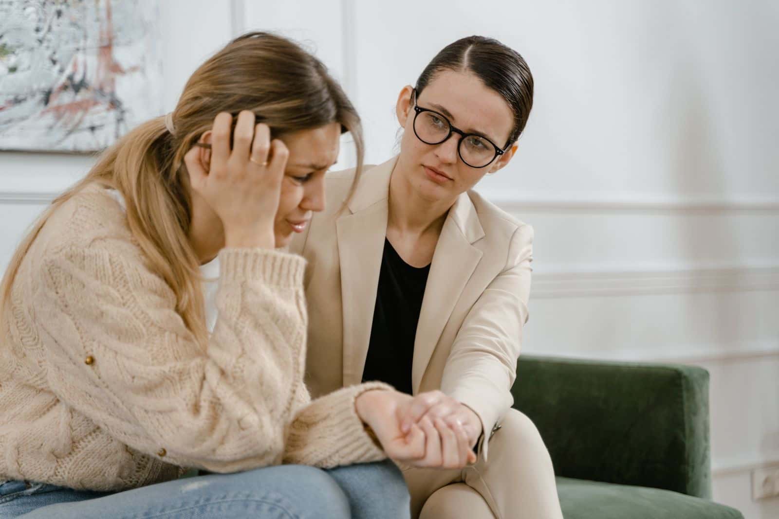 A woman comforting a worried friend who holds her head in her hand